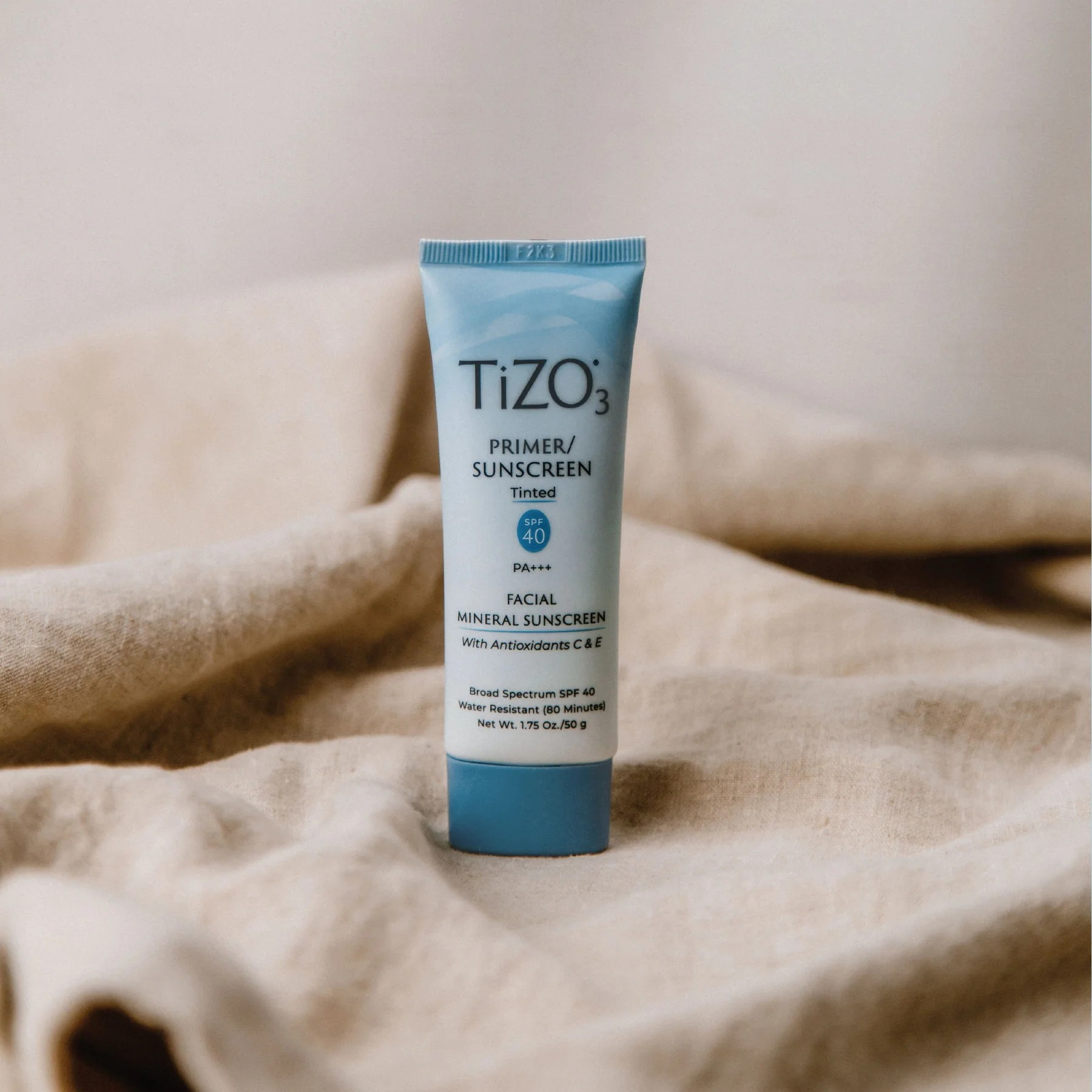 TiZO Facial Primer - Tinted SPF 40 product tube standing on beige cloth