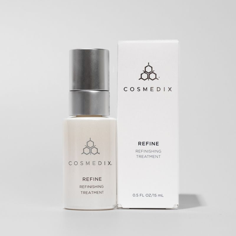 COSMEDIX's Refine Refinishing Treatment white product bottle with silver cap, standing beside white product box, against light grey background