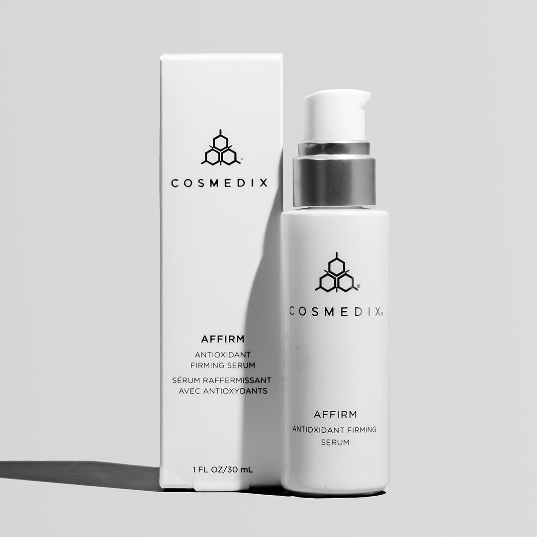 COSMEDIX's Affirm Antioxidant Firming Serum in white bottle with pump dispenser, standing next to white product box