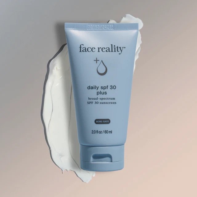 Face Reality's daily spf 30 plus blue product tube against white-colored product swatch and beige background.