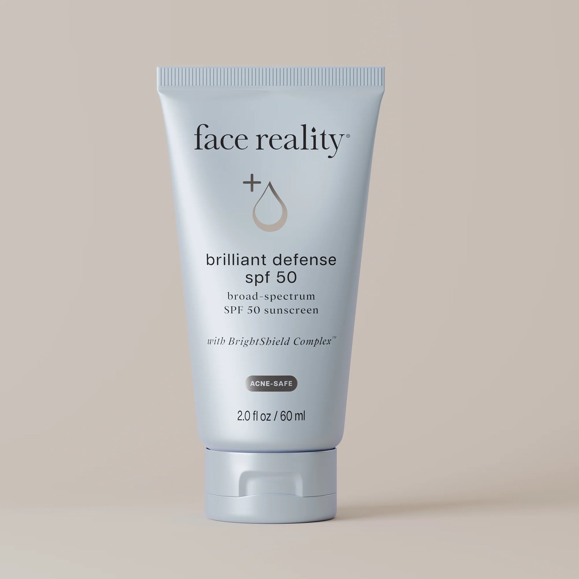 Tube of 'face reality' Brilliant Defense SPF 50 sunscreen on a beige background