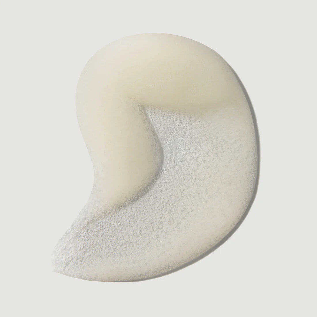 Close up of white facial scrub swatch on a light gray background