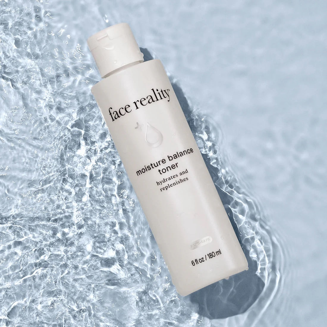 Face Reality's moisture balance toner bottle laying in water
