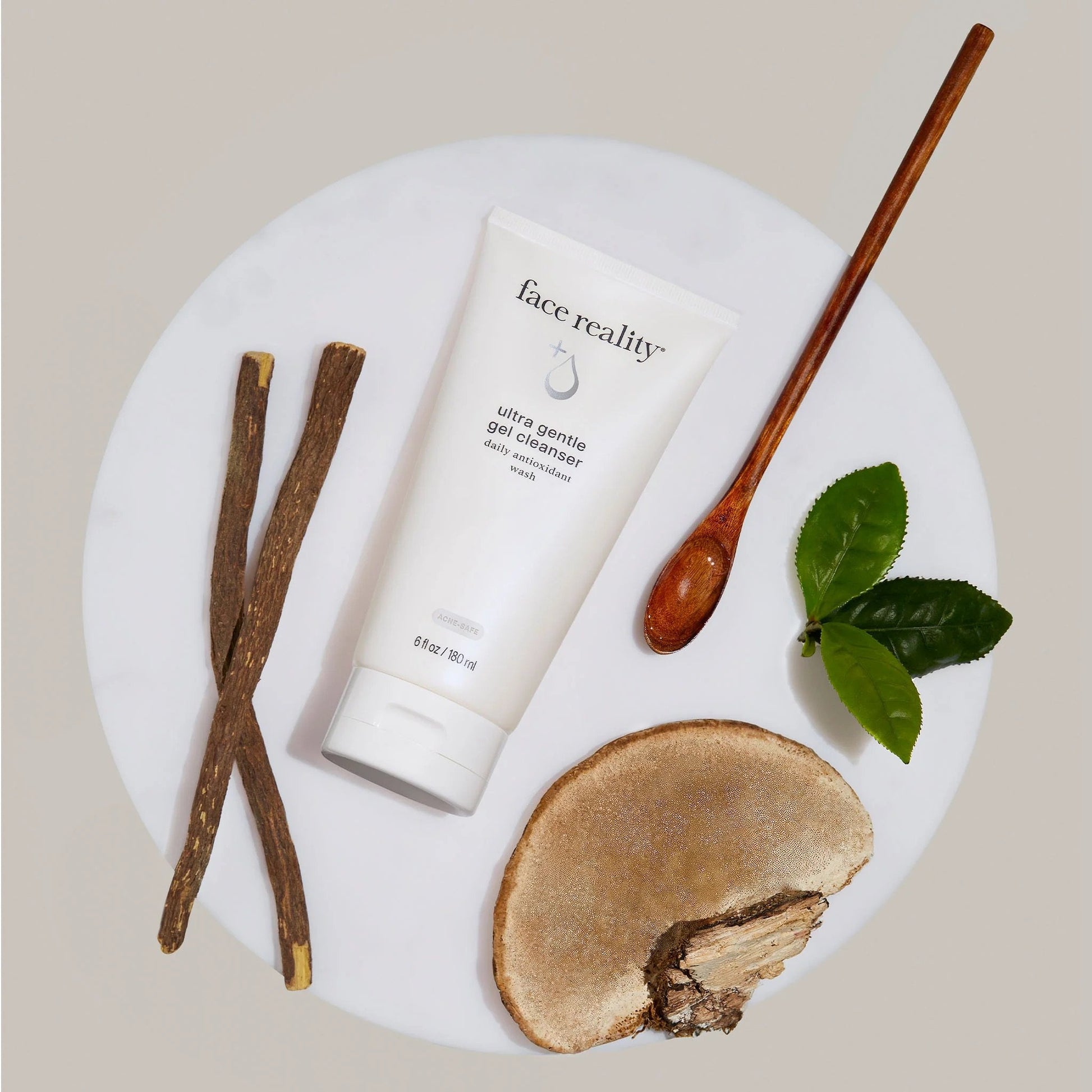 Face Reality's ultra gentle gel cleanser cream-colored product bottle surrounded by brown and green items found in nature