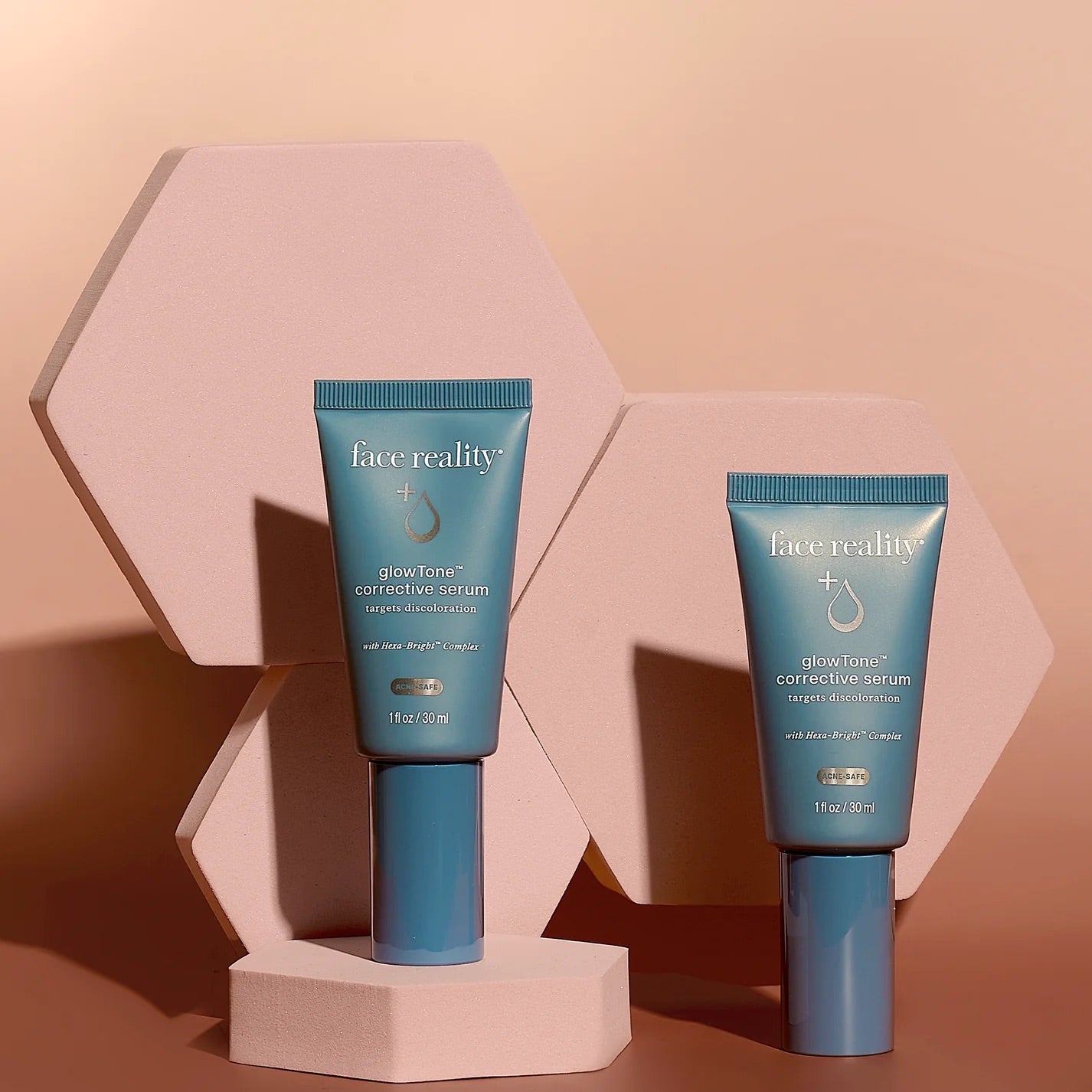 Face Reality's glowTone corrective serum, two blue product tubes pictured against hexagon background