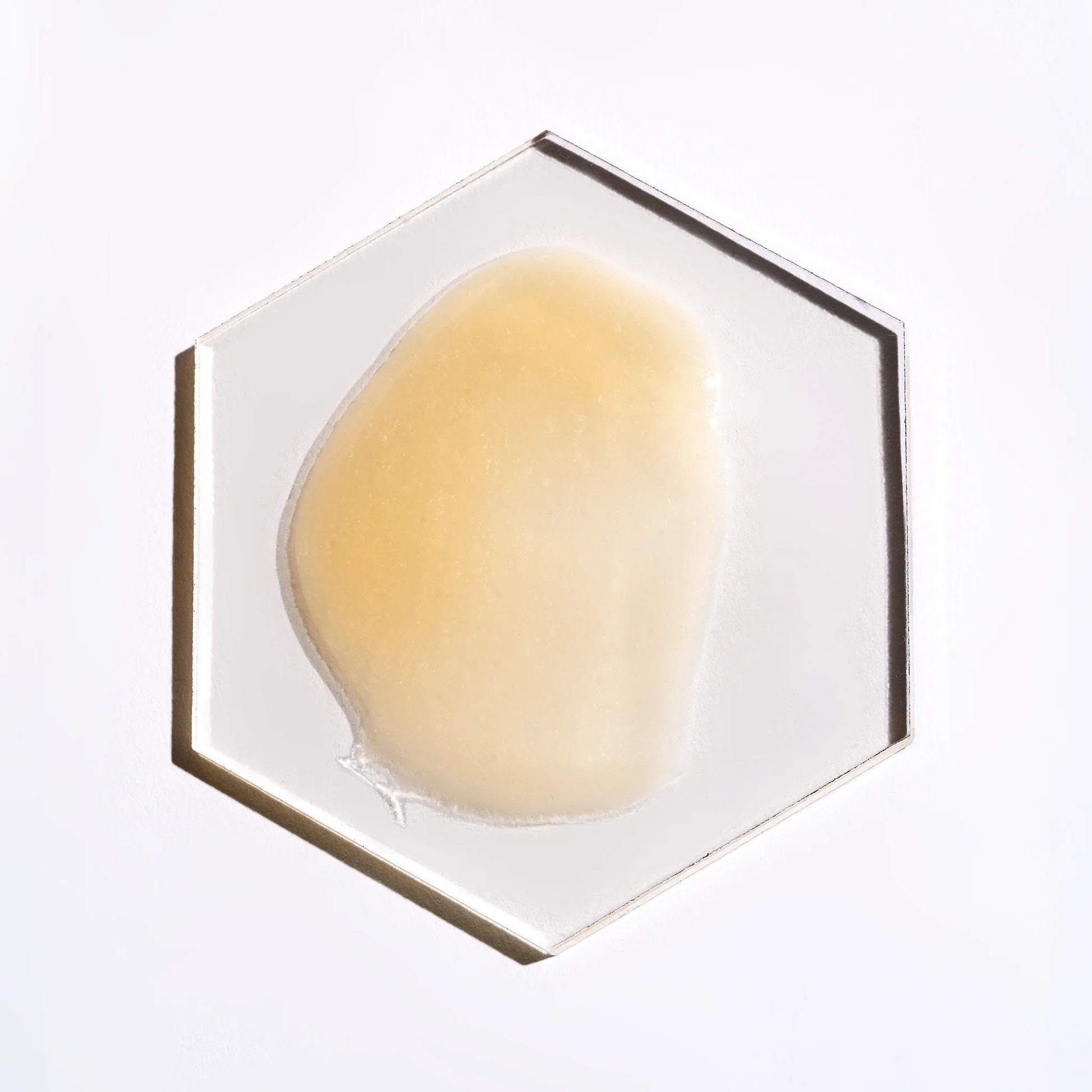 Face Reality's glowTone corrective serum cream-colored product swatch on glass hexagon