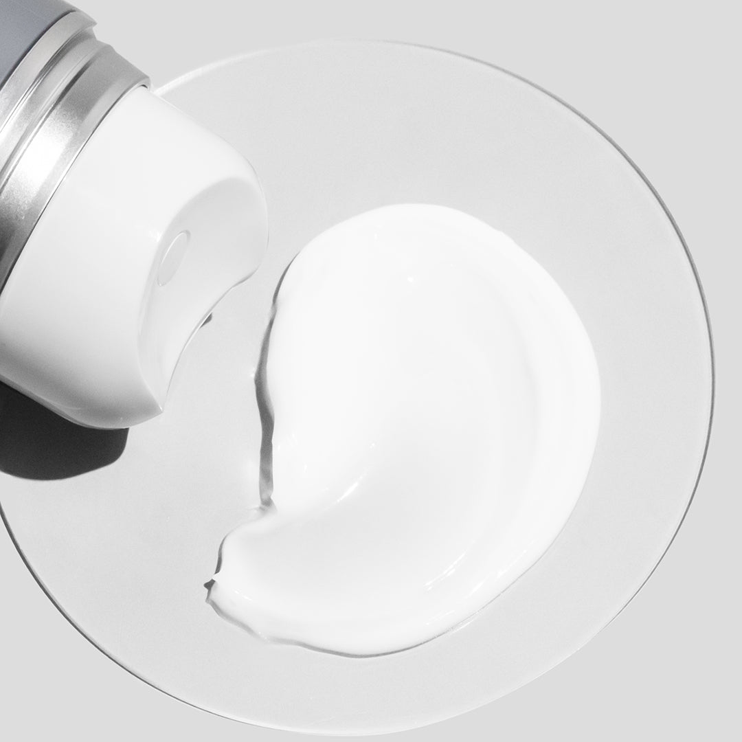 COSMEDIX's Harmonize Microbiome Boosting Moisturizer zoomed in view of white colored product swatch on petri dish with a light grey background