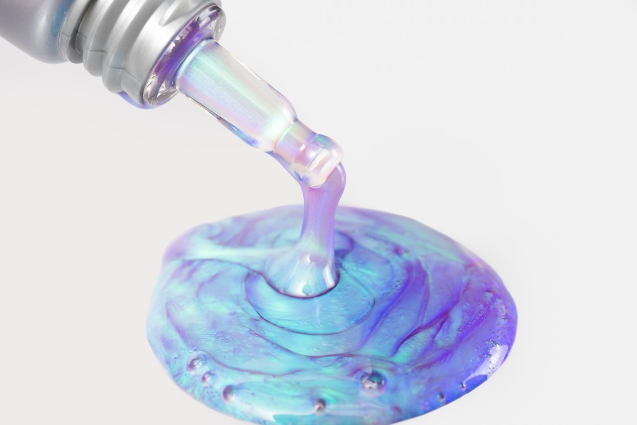 COSMEDIX's Opti Crystal Liquid Crystal Eye Serum iridescent liquid being dispensed onto white background
