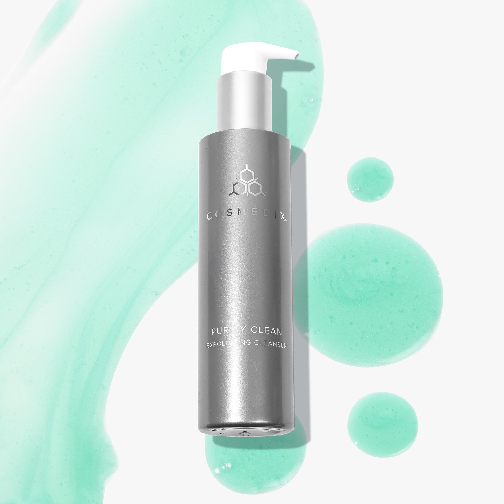 COSMEDIX's Purity Clean Exfoliating Cleanser grey product bottle with white pump dispenser against teal product swatches and a white background