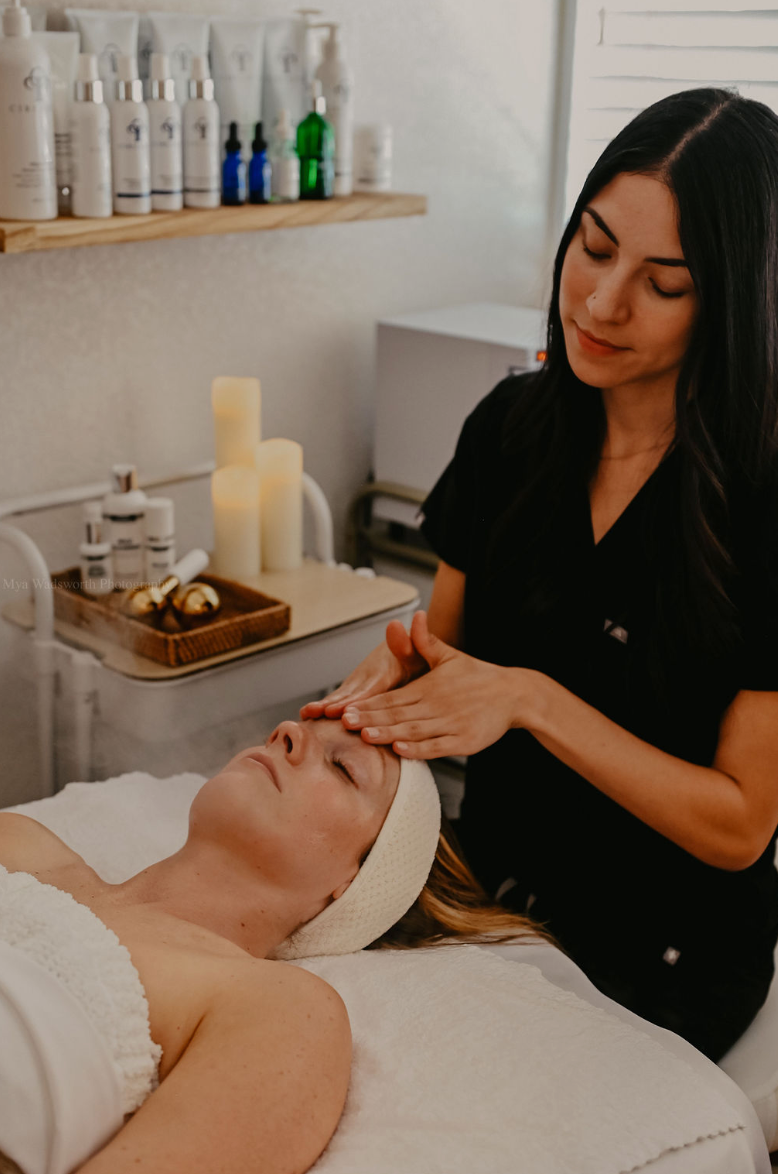 Woman receiving a facial treatment from an esthetician in a spa setting at Luna Luxe Aesthetics