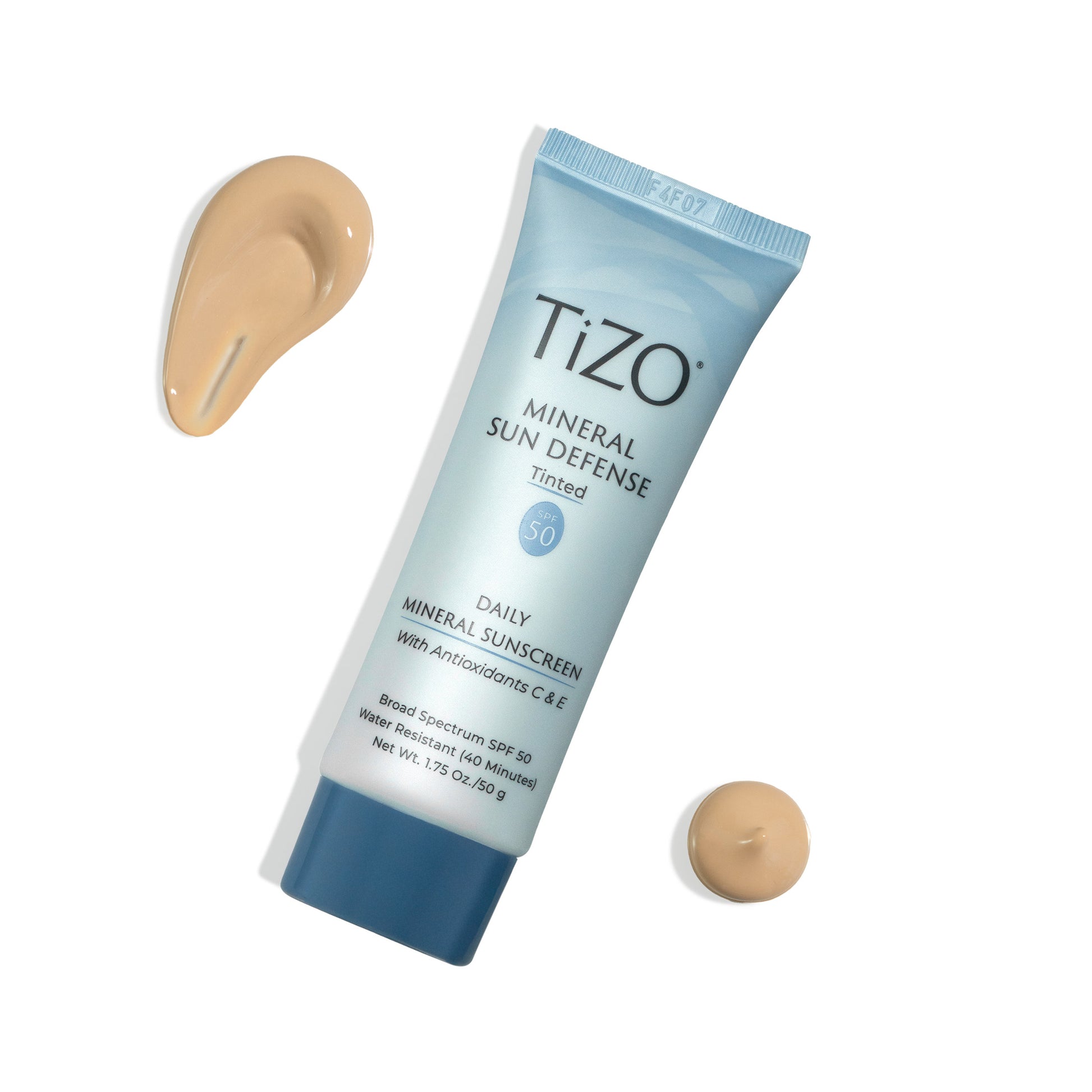 TiZO Mineral Sun Defense Tinted SPF 50 product tube with beige colored product swatches against white background