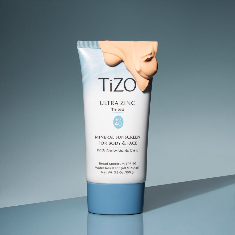 TiZO Ultra Zinc Body & Face - Tinted SPF 40 product tube with beige colored product on top of the tube, against a blue background