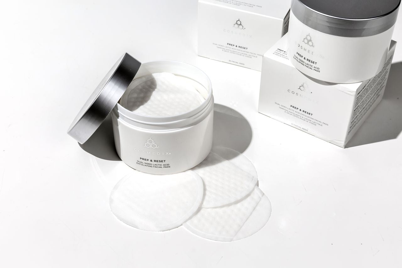 COSMEDIX'S Prep & Reset Dual-Sided Lactic Acid Exfoliating Facial Pads white colored container with open lid displaying product pads and other packaging against a white background