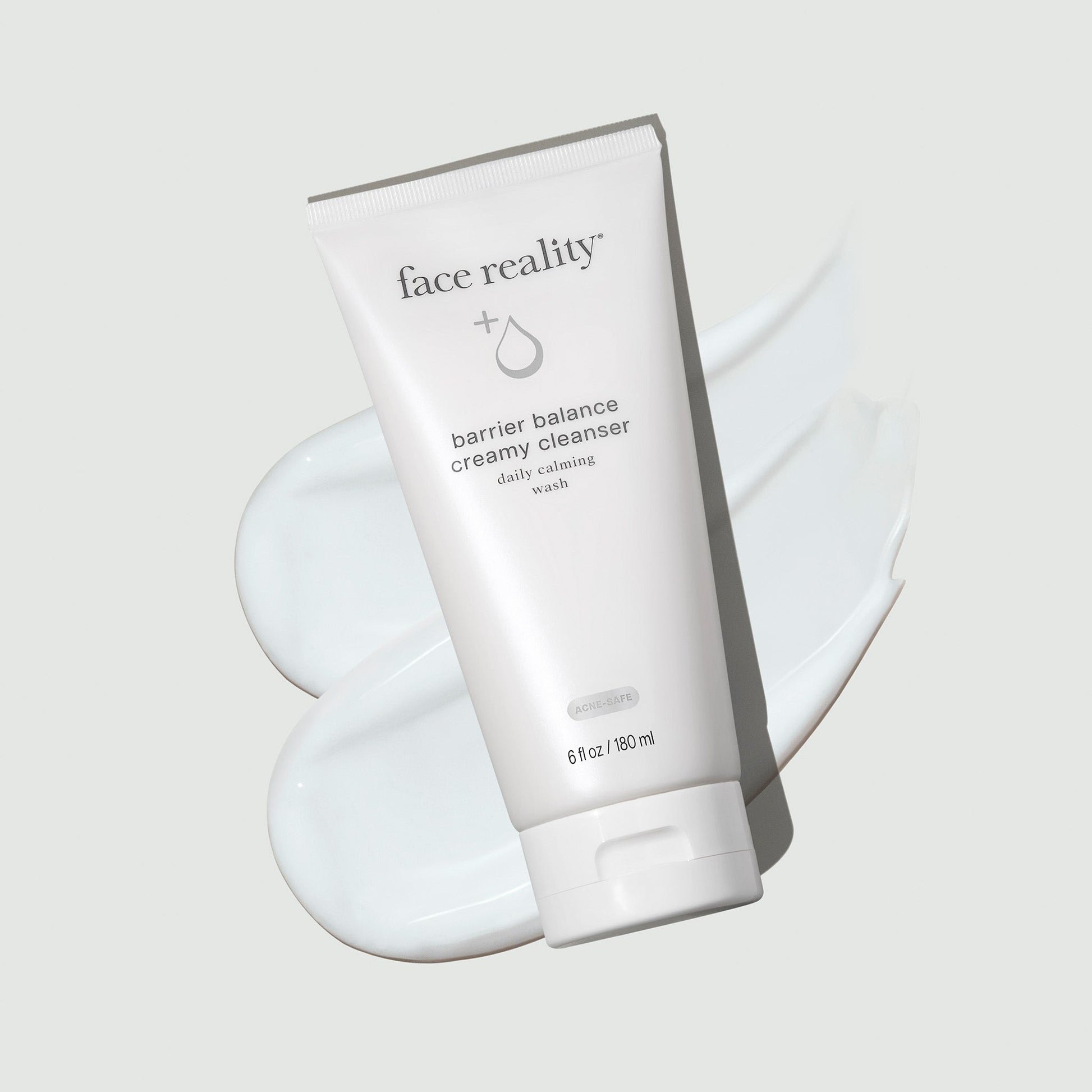 Face Reality's barrier balance creamy cleanser in white product tube laying on white colored product swatch, with a cream-colored background
