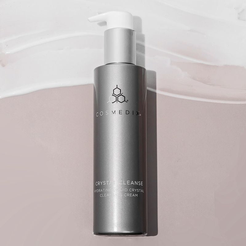 COSMEDIX's Crystal Cleanse grey-colored product bottle with white pump dispenser against beige background with white-colored product swatch